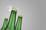 Three green beer bottles on grey background
