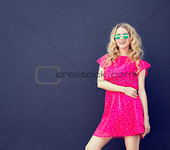 Summer Fashion Woman in Pink Dress at Dark Wall
