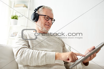 senior man with tablet pc and headphones at home