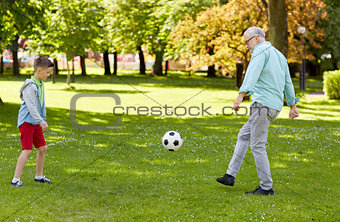 old man and boy playing football at summer park