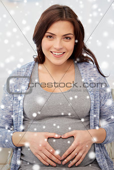 happy pregnant woman making heart gesture at home