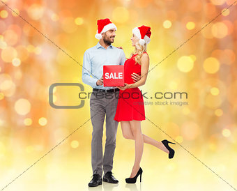 happy couple in santa hats with red sale sign