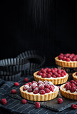 Delicious raspberry mini tarts on dark background