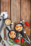 Fried eggs with tomatoes in frying pans