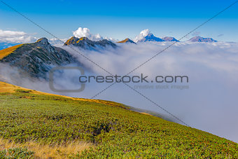 Clouds cover mountain tops at autumn evening time.