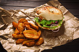 hamburger and potato wedges on wooden table