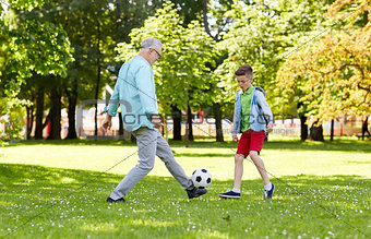 old man and boy playing football at summer park