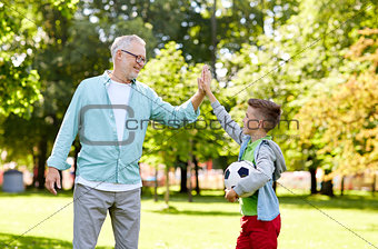 old man and boy with soccer ball making high five