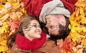 close up of smiling couple lying on autumn leaves