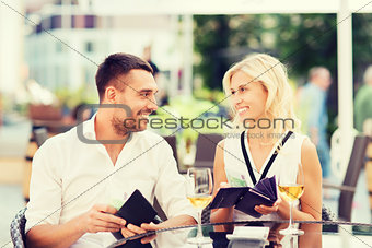 happy couple with wallet paying bill at restaurant