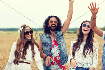 happy young hippie friends dancing on cereal field