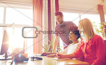 happy creative team with computer in office