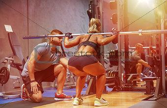man and woman with bar flexing muscles in gym