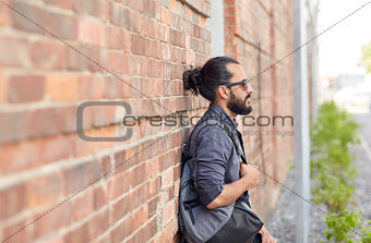 man with backpack standing at city street wall