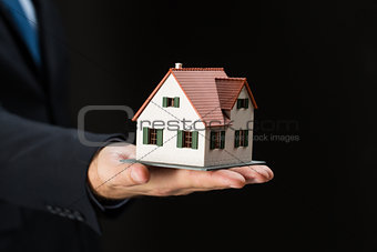 close up of businessman hand holding house model