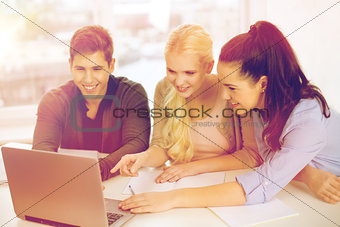 three smiling students with laptop and notebooks