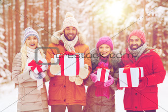 happy friends with gift boxes in winter forest