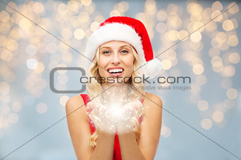 happy woman in santa hat with fairy dust on hands