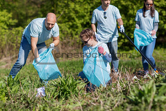 volunteers with garbage bags cleaning park area