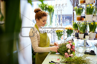 smiling florist woman making bunch at flower shop