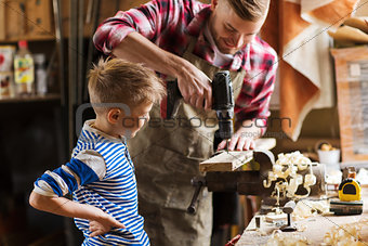 father and son with drill working at workshop