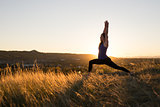 Woman doing yoga warrior I pose during sunset