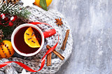 Traditional winter beverage mulled wine. Christmas drink. Gray background with knitted scarf