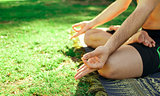 Hands and legs of man meditating on the grass
