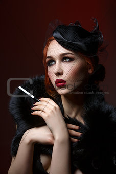 Beautiful girl with smoky eyes and red lips holding cigarette