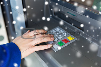 close up of hand entering pin code at cash machine