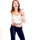 young girl measuring herself in studio isolated on white background happy smiling, holding bottle of water wearing sport clothers, lifestyle people concept
