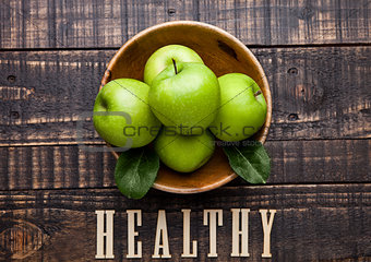 Green organic healthy apples in bowl on wooden board