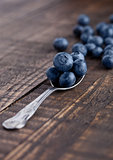 Blueberries on old spoon on grunge wooden board