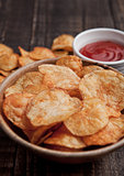 Bowl with potato crisps chips and ketchup on wooden board