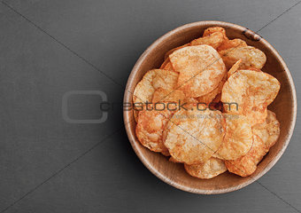 Bowl with potato crisps chips on black stone board