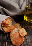 Bowl with potato crisps chips and olive oil on wooden board