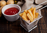 Fried french fries chips in fryer with ketchup on wood