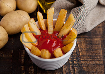 Fried french fries chips in fryer with ketchup on wood