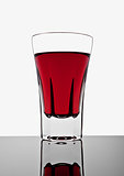 Glass with red drink on white background