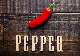 Red hot mexican pepper on wooden board with letters