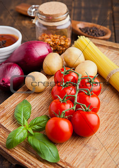 Fresh tomatoes with vegetables and basil on wooden board