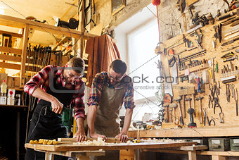 carpenters with drill drilling plank at workshop