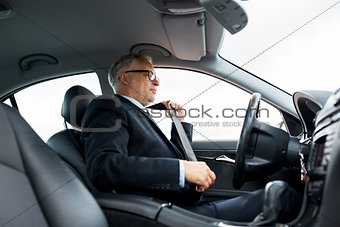senior businessman fastening car seat belt