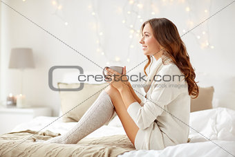 happy woman with cup of coffee in bed at home
