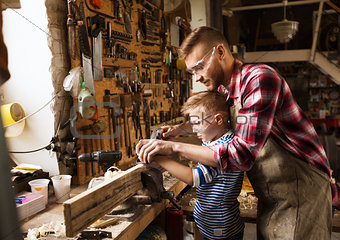 father and son with plane shaving wood at workshop