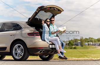 happy man and woman with road map at hatchback car