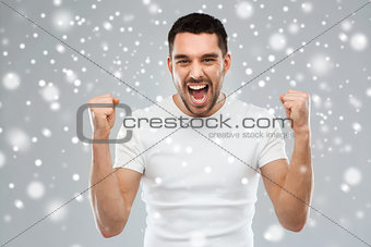 angry young man holding fists over snow