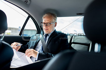 senior businessman with papers driving in car