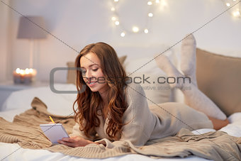 happy young woman with notebook in bed at home