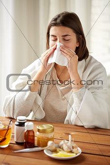 sick woman with medicine blowing nose to wipe